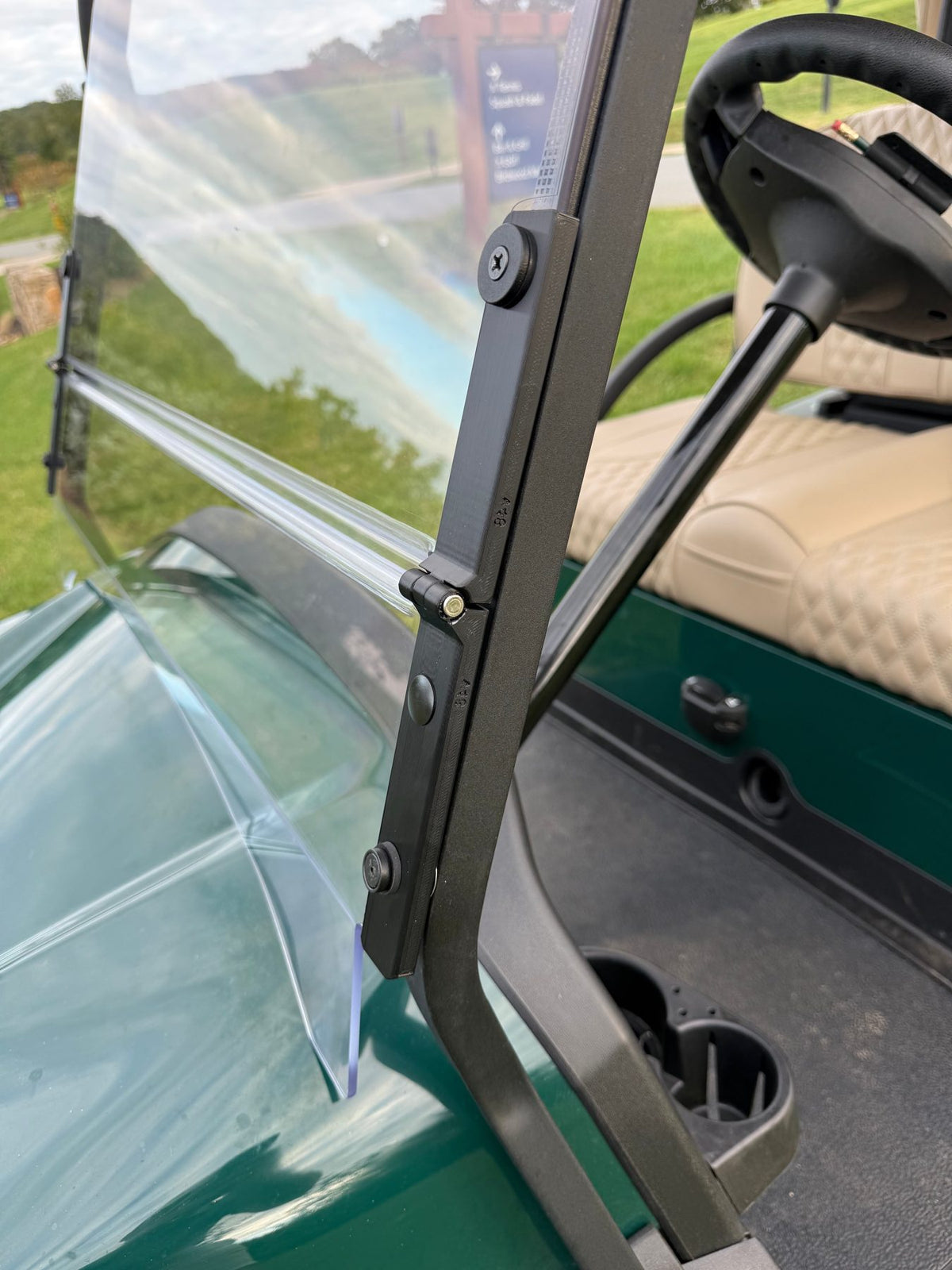 Close-up of the Evolution pivot hinge on a Club Car Onward LSV windshield: a mechanical, UV-resistant hinge with no adhesive